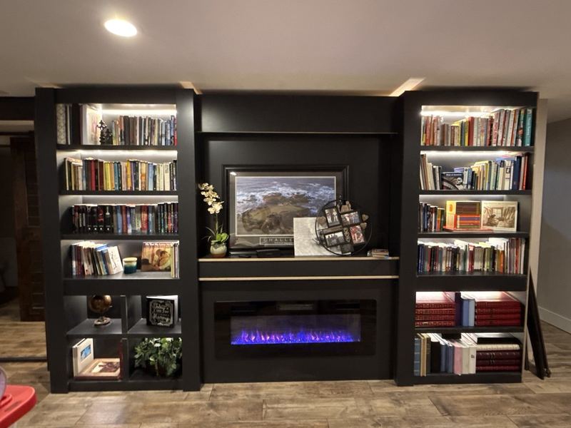 Floor-to-ceiling black built-in bookshelves flanking an electric fireplace